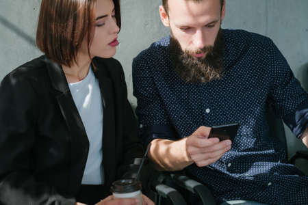 Business colleagues. Break from work. Bearded man with smartphone. Woman with coffee.の写真素材