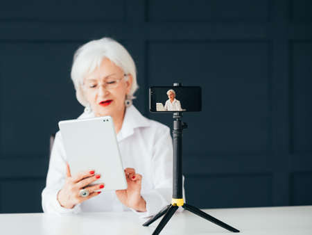 Senior lady blogger. Trendsetter lifestyle. Elderly woman with tablet making video tutorial.
