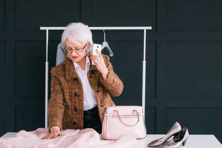 Successful senior woman. Stylish showroom. Glamor and elegance. Wealthy elderly lady choosing new outfit.の写真素材