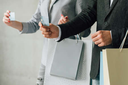 Urban shopping lifestyle. Fashionist hobby. Man and woman showing credit cards and bags variety.の写真素材