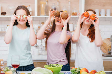 Home cooking leisure. Evening fun and relaxation. Young females covering eyes with food while preparing meal.の写真素材