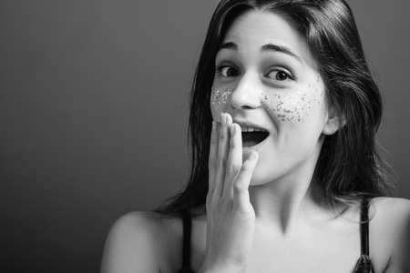 Excited young woman. Wow. Open mouth stare. Hand at lips. Black and white portrait. Copy space.の写真素材
