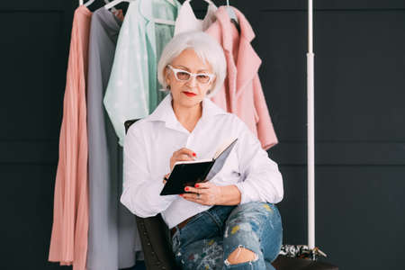 Personal fashion stylist. Successful business. Confident senior lady making notes in day planner.の写真素材
