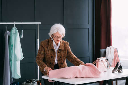 Successful senior woman. Fashion style female coach. Confident elderly lady analyzing wardrobe.の写真素材