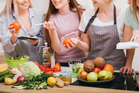 Culinary courses. Communication and food education. Women choosing organic vegetables and learning healthy diet recipes.の写真素材