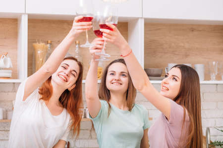 Girls party fun. Celebrating women. Happy young females clinking red wine glasses.の写真素材