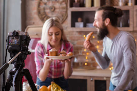 Culinary blog. Baking hobby. Couple shooting video tutorial. Man and woman with fresh cakes and...