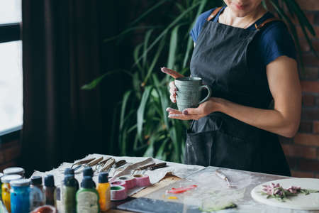 Break time. Rest and relaxation. Smiling lips. Female artist with mug. Midsection. Art studio workspace.の写真素材