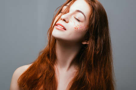 Peace of mind. Freedom of youth. Young redhead female. Eyes closed. Naked shoulders.の写真素材