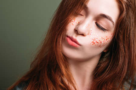 Young woman portrait. Skeptical facial expression. Redhead female with pursed pout lips looking...