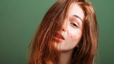 Young redhead woman. Tired look. Boredom expression. Copy space on green background.の写真素材