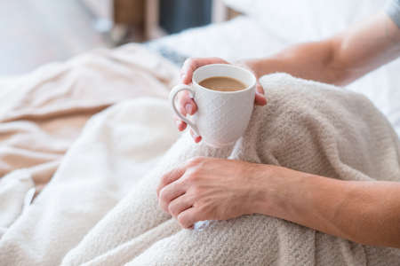 Morning latte. Wake up drink. Man with cup in bed. Relaxation and leisure time. Bedroom coziness.