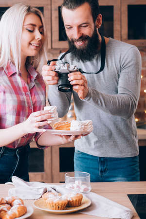 Food blogging. Couple lifestyle. Man taking photos of fresh homemade cakes and pastries.の写真素材