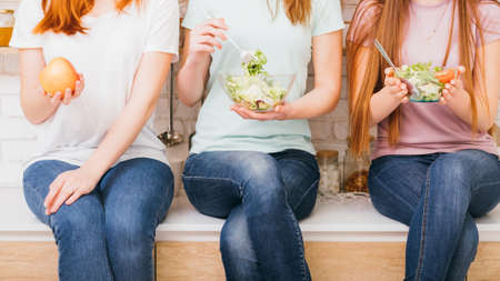 Females on diet. Healthy nutrition lifestyle. Women with fresh vegetables salad bowls. Apple appetizer.の写真素材