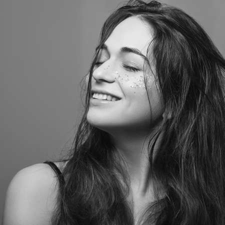 Wavy hair beauty. Care and treatment. Smiling young female. Eyes closed. Black and white.