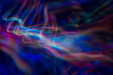 Blurry abstract background with wavy multicolor lines. Neon lights in motion. Defocused lens flare glow.の写真素材