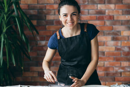 Artist studio. Clay handicraft in process. Smiling young woman with modeling tools at workplace...