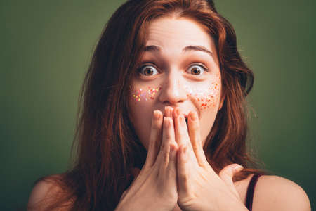 Astounded woman portrait. Disbelief facial expression. Young female with wide open eyes. Hands covering mouth.の写真素材