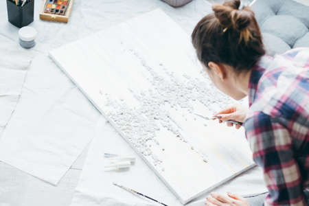 Art craft hobby. Leisure and lifestyle. Woman with textured painting on floor. Modeling tool in...