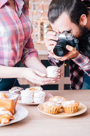 Food photographer and assistant at work. Man and woman taking photo of meringue. Cakes and pastries...