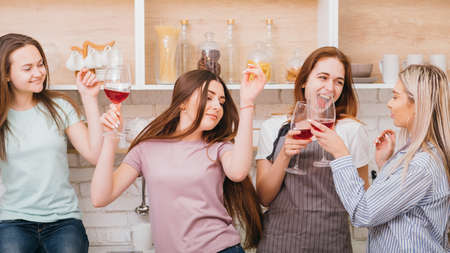 Women hanging out. Casual party fun. Alcohol abuse. Young females having good time drinking red wine.の写真素材