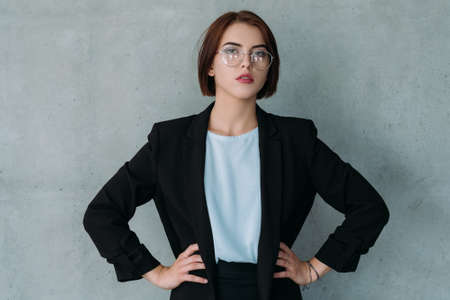 Portrait of young lady boss standing confidently with hands on the hips. Professional achievements. Female power in business.の写真素材