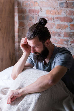 Monday morning again. Drowsiness. Man sitting in bed. Rubbing eye, looking tired and sleepy. Loft...