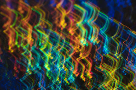 Glowing multicolor angled lines on dark background. Blurred neon lights. Lens flare effect.の写真素材