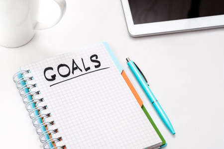 Business project. Ambition and aim. Think and dream big to reach goals. List of objectives to achieve. Notepad and tablet.の写真素材