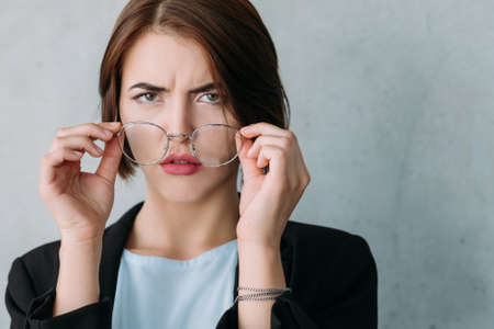 Closeup of young business lady looking confused, taking off glasses. Professional disagreement and disappointment.の写真素材