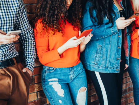 Millennials habits. Young people standing in row, using smartphones, obsessed with new technology trends.の写真素材