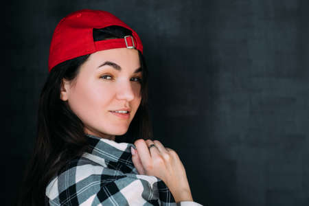 Closeup portrait of millennial lady in checked shirt and red baseball cap. Emotional woman posing with flirty facial expression.の写真素材