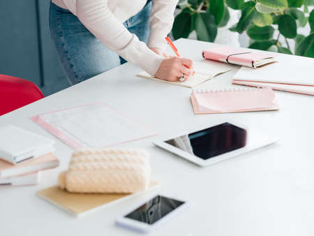 Social network business. Internet marketing. SMM woman at workplace making notes in schedule. Tablet and smartphone.の写真素材