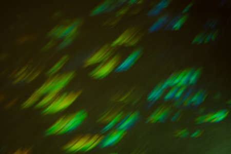 Glowing defocused green lights on dark background. Blurred multicolor lines. Illuminated lens flare