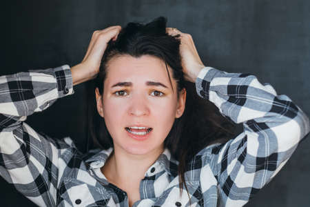 Closeup portrait of brunette lady. Emotional young woman clutching her head terrified. Stressed...