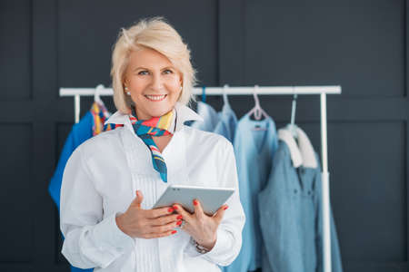Senior business woman. Modern female lifestyle. Lady with tablet at showroom. Elegance, confidence and independence.の写真素材