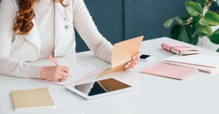 Social media marketing. SMM expert at work scheduling job. Woman writing. Office supplies and technology tools at hand.の写真素材