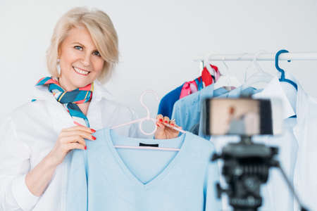 Senior lady style. Fashion trends coach. Smiling aged woman shooting video for personal blog. Elegance and confidence.の写真素材