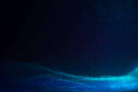Abstract light waves with glitter effect. Shiny blurry blue lines on dark background. Defocused soft...