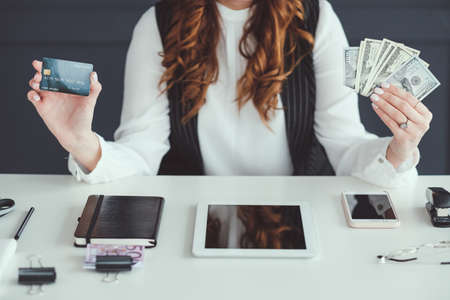 Successful SMM woman. Money making business. Female at workplace holding credit card and dollar bills. Good profit.の写真素材