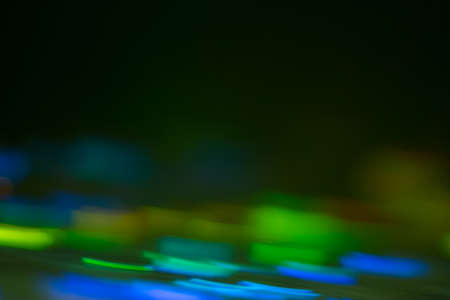Bokeh blue and green lights reflected on surface. Defocused lens flare spots. Abstract background.