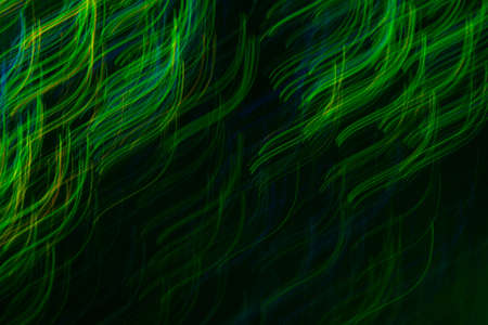 Blurry neon green curved lines on dark background. Lens flare lights in motion. Bokeh abstract...