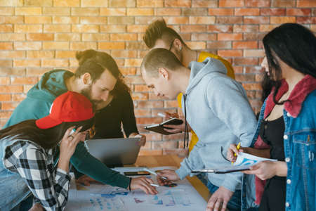 Millennials working on startup project in openspace office, modern environment. Smart young people brainstorming.の写真素材