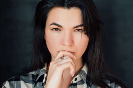 Young woman portrait. Intense look. Fixed gaze. Speculation. Thoughtful brunette looking at camera....
