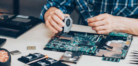 Computer repair service. Hardware support. Electronic technology. Cropped shot of technician fixing laptop cooler.の写真素材