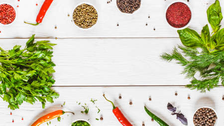 Frame of herbs and spices on white wooden background, flat lay. Top view on assortment of different...