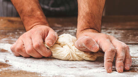 Bread making process. Closeup of man hands kneading dough. Baker cooking pastry. Culinary courses and food preparation.の写真素材
