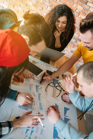 Sales analysis. Young business team at work studying graphs charts. Millennials brainstorming. Colleagues collaboration.の写真素材