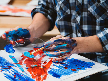 Modern art school. Cropped shot of lefthanded male student mastering skills, using palette, brush and sketch board for painting.の写真素材