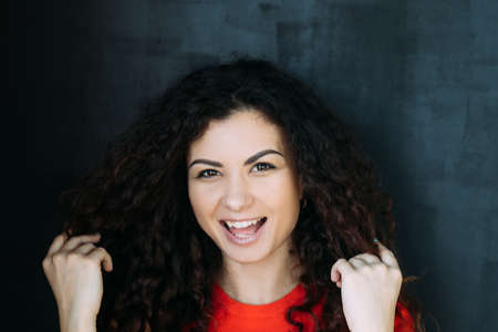 Closeup portrait of joyful smiling brunette lady with curly hair. Beautiful emotional young woman....